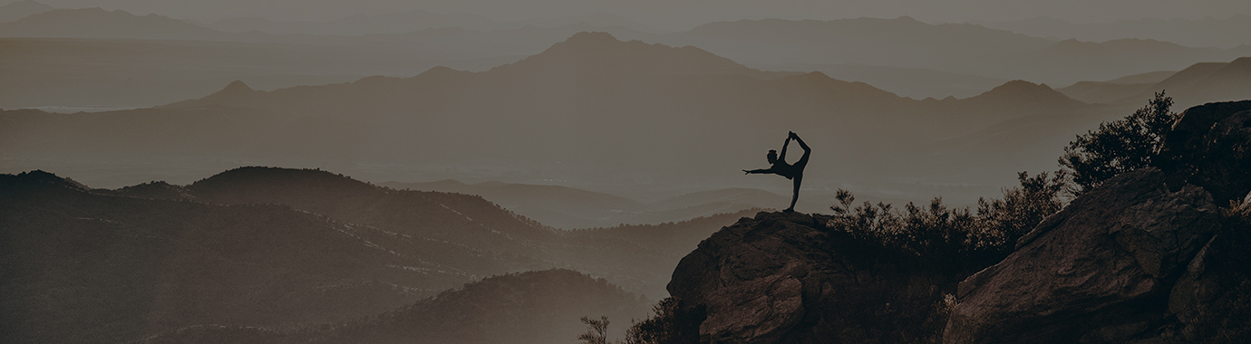 A ballet dancer stretching surrounded by mountains