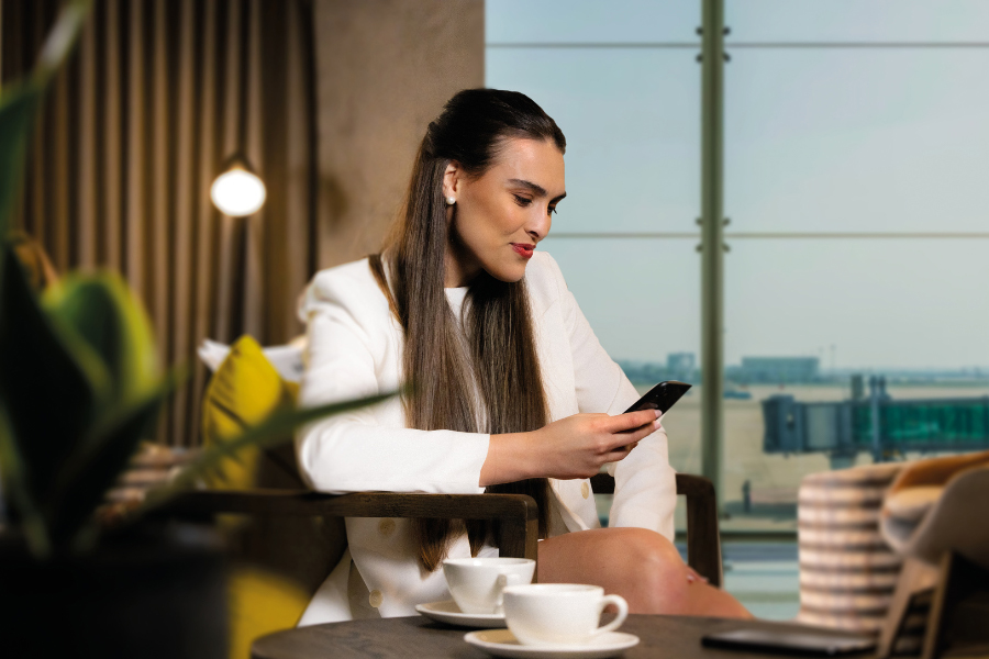 A woman sitting at a table, looking at her phone.