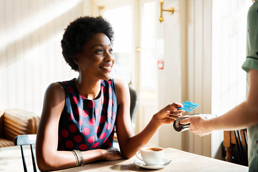 Woman using tapping card reader with contactless payment in café