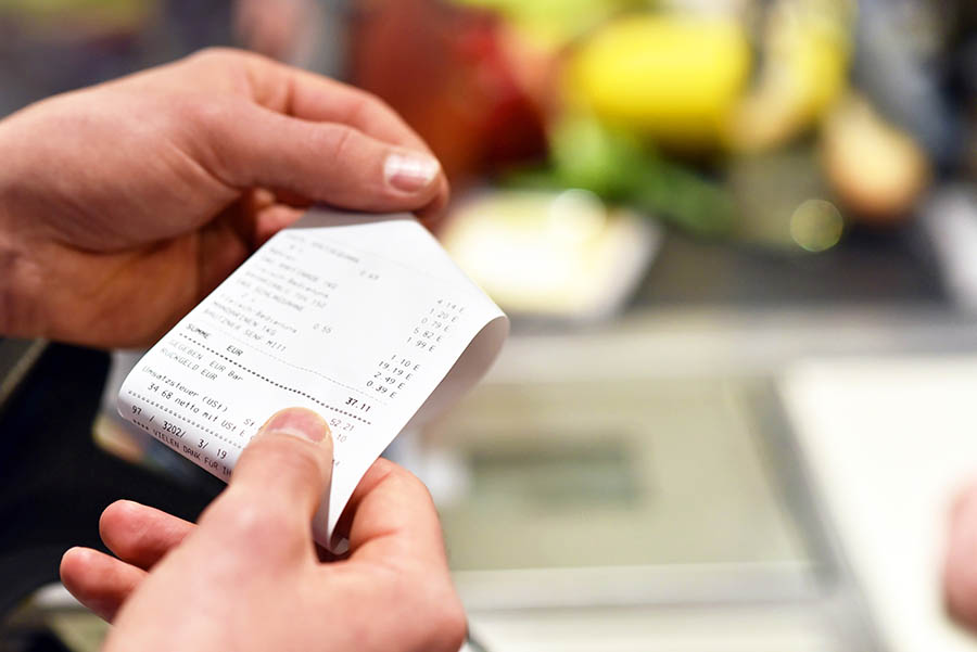 Up close image of a pair of hands holding a receipt in a supermarket