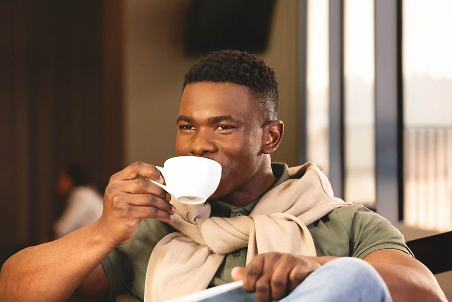 A man drinking from a cup, at an airport lounge.