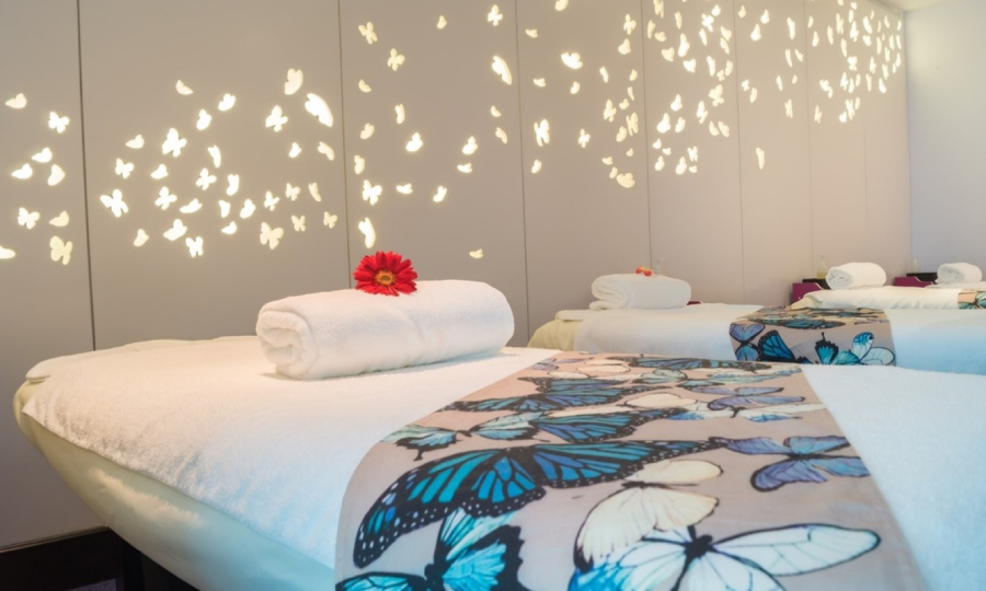 A serene massage room at TranSpa, Changi Airport, Singapore, adorned with white towels and butterflies blanket