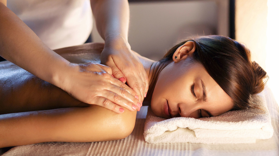 A woman enjoying a relaxing back massage at a spa, surrounded by soothing ambiance and skilled therapists